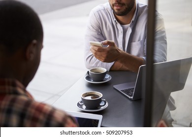 Crop Shot Of Two Male Friends With Coffees Outside Cafe