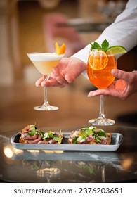 Crop staff with appetizing dish and aperitif cocktails for dinner on blurred background