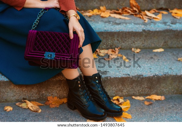 Crop of trendy autumn woman`s fashion outfit: purple\
velour quilted bag, blue midi skirt, black chunky ankle boots.\
Copy, empty space for text