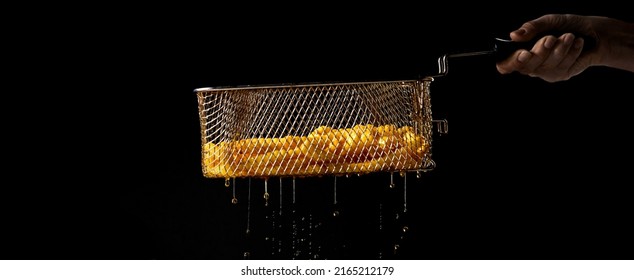 Crop unrecognizable chef holding metal deep fryer basket with French fries and dripping oil against black background - Shutterstock ID 2165212179