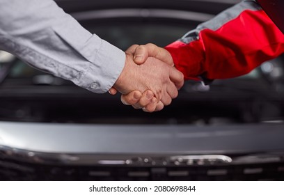 Crop unrecognizable male client and technician in uniform shaking hands after making deal in automobile repair service - Powered by Shutterstock