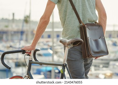 Crop of unrecognizable man with crossbag walking with his fixie in sunlight. Bokeh.