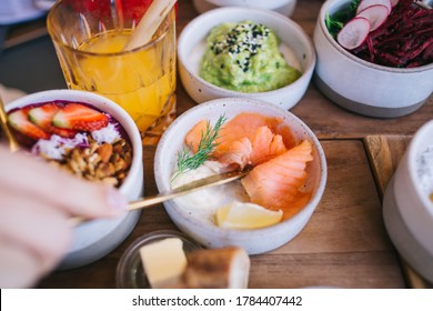 Crop Unrecognizable Person Having Delicious Meal Of Salmon And Other Dishes From Small Round Bowls On Wooden Table