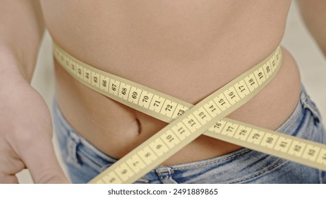 Crop woman measuring waistline. Faceless shot of shaped woman measuring waist with tape. - Powered by Shutterstock