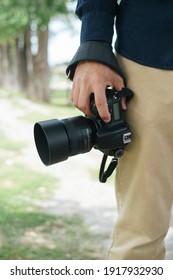Croped image of digital camera while the male photographer hold it at his lag with copy space.