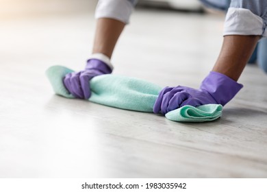 Cropped Of African American Man House-keeper Erasing Floor, Cleaning House Alone, Copy Space. Closeup Of Unrecognizable Black Guy Hands Cleaning Floor With Dust Cloth, Wearing Colorful Rubber Gloves