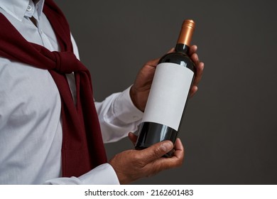 Cropped of african american winemaker or sommelier holding wine bottle. Successful male entrepreneur or businessman. Viticulture and winemaking. Isolated on grey background. Studio shoot. Copy space
