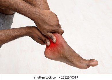 Cropped of african man rubbing his ankle over white background, copy space