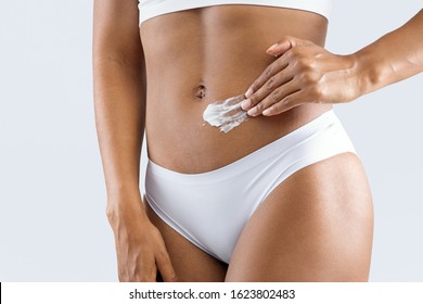 Cropped Of Afro Lady Applying Anti Cellulite Cream On Her Well Fit Belly, Grey Background