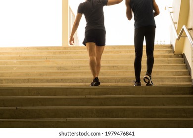 Cropped Back View Of Two Young Athletes Walk Up The Stairs, People Walking To The Bright Light Outdoor. Success Ideas Lifestyle And Sport Concept.