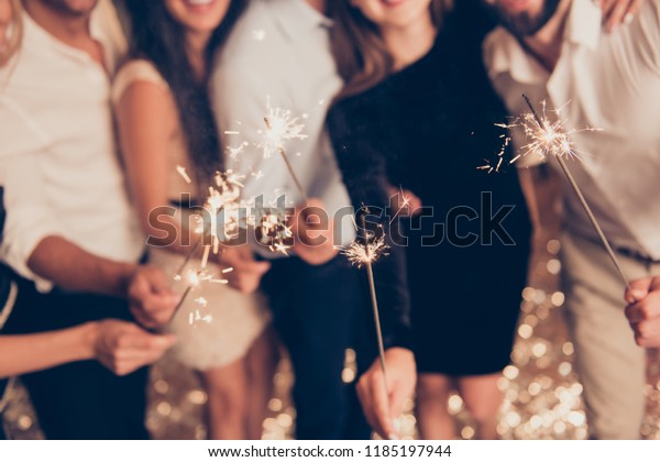 Cropped bengal fire sticks,\
sparkling, burning, elegant classy ladies and gentlemen\'s hands\
holding fire-sticks together, meeting, team, greetings,\
congrats