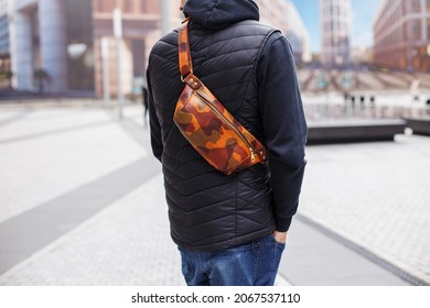 A Cropped Beyond Recognition Man Holding His New Brown Leather Banana Bag In The City. Men's Leather Hip Bag Over The Shoulder Waist Bag Made Of Genuine Leather. The Man Is Standing With His Back