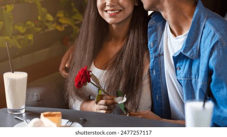 Cropped of black guy and girl are seated at a table, each holding a rose in their hands. They appear to be engaged in a conversation or intimate moment while focusing on the roses. - Powered by Shutterstock