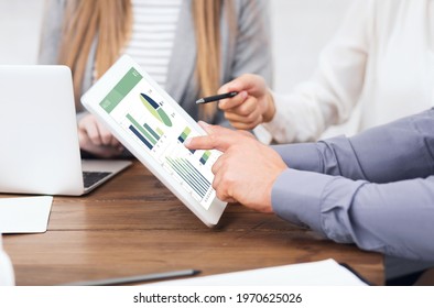 Cropped of business team men and women analysing market, using financial application on digital tablet in office, making business prognosis or investigating markets and stocks online - Shutterstock ID 1970625026
