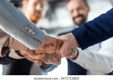 Cropped of a business teams hands clasped together in a fist bump, showcasing their camaraderie and unity. The image captures the essence of teamwork and collaboration in a professional setting. - Powered by Shutterstock