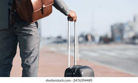 Cropped of businessman is walking with his luggage outside a modern airport. The mood is dynamic and professional, highlighting travel and business with a sleek airport backdrop. - Powered by Shutterstock