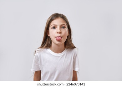 Cropped of caucasian little girl sticking out tongue and looking at camera. Female child of zoomer generation. Concept of modern youngster lifestyle. Isolated on white background in studio. Copy space