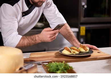 Cropped Chef Cook Take Photo Of Dish Prepared By Him, Using Smartphone. Tasty Yummy Meal On Plate Is Going To Be Served For Restaurant Guests