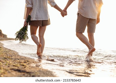 Cropped close up back view young couple two family man woman in white clothes hold flowers bouquet hand walk in water waves at sunrise over sea beach ocean outdoor seaside in summer day sunset evening - Powered by Shutterstock