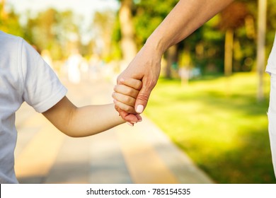 Cropped close up of a boy and grandmother holding hands. CLose up of hands of a child and parent on the walk at the local park in summer family love bonding children parenting family weekend leisure