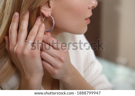 Cropped close up of a female trying on diamond earrings at jewelry shop