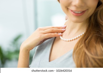 Cropped close up of a happy woman smiling joyfully wearing pearl necklace copyspace elegance luxury wellbeing rich wealth consumerism buying shopping jewelry accessories expressive emotional.