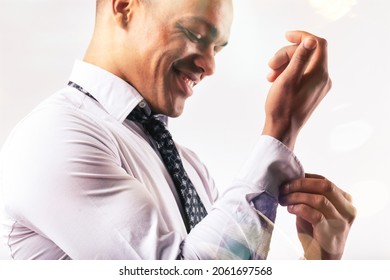 Cropped Close Up Of A Happy Young Black Man Dressing Doing Up The Button On The Sleeve Of His Shirt In A High Key Portrait