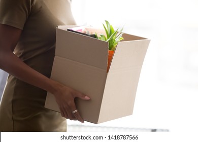 Cropped close up image mixed race female hands holding cardboard box with belongings stuff new employee member starting career in company having first working day. Newcomer hiring employment concept