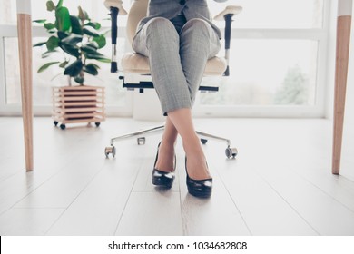 Cropped close up photo of healthy beautiful elegant woman's legs wearing high-heeled shiny black shoes, the woman is sitting in office at the table on modern luxurious armchair - Powered by Shutterstock