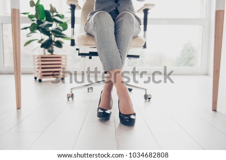 Cropped close up photo of healthy beautiful elegant woman's legs wearing high-heeled shiny black shoes, the woman is sitting in office at the table on modern luxurious armchair 商業照片 © 