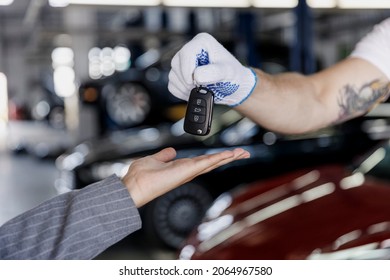 Cropped Close Up Photo Shot Of Young Car Mechanic Man Caucasian Male Hands Talk With Female Driver Owner Give Keys Fob Keyless System Woman Work In Vehicle Repair Shop Workshop Indoors Focus On Key