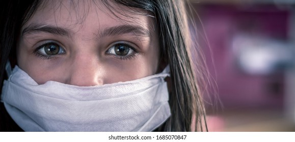 Cropped close up portrait of young girl looking sad,wearing medical surgical mask to protect from Covid-19 Corona virus or air pollution. Female child wearing protective mask,health and safety concept