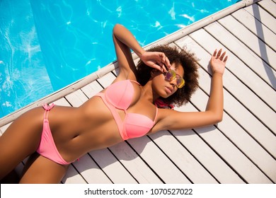 Cropped close up top above overhead view photo of sexual figure shape sporty multi-ethnical afro posing lady wearing stylish trendy bikini lying on white wooden floor by the blue pool