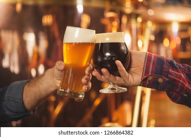 Cropped close up of two men clinking beer glasses together, celebrating at the beer pub. Professional brewers toasting with their beer glasses. Success celebration, oktoberfest festival concept - Powered by Shutterstock