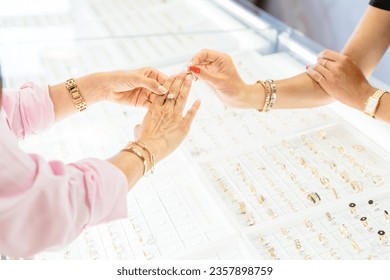 Cropped close up of a unercognizable woman trying on an engagement ring and saleswoman helping her at the jewelry store. - Powered by Shutterstock