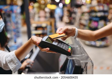 Cropped close up woman hand arm shopping at supermaket put credit card to wireless modern bank payment terminal process acquire payments near cashier checkout inside store. People purchasing concept