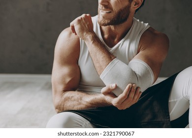 Cropped close up young ill sporty athletic sportsman man wear white tank shirt black shorts feel bad suffer from pain spasm in hand elbow shoulder warm up train indoor at gym Workout sport concept - Powered by Shutterstock