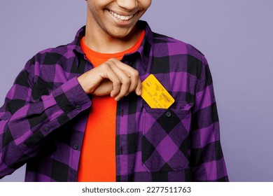 Cropped close up young man of African American ethnicity wear casual shirt orange hat hold in hand mock up of credit bank card put into pocket isolated on plain pastel light purple color background - Powered by Shutterstock