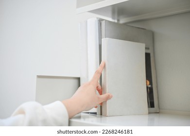 Cropped and close-up hand image of a young Asian woman choosing book on the bookshelf in the library or bookstore. education concept - Powered by Shutterstock