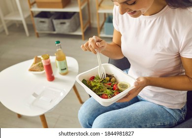 Cropped Close-up Of Happy Smiling Young Woman In Casual Wear Having Takeout Lunch At Home And Eating Fresh Vegetable Salad From Plastic Container. Healthy Food, Vegetarian Diet, Enjoying Meals Concept