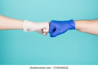 Cropped close-up photo of two people showing how to resist ncov wearing gloves white and blue bump fists isolated on turquoise background. Patient and doctor in hospital