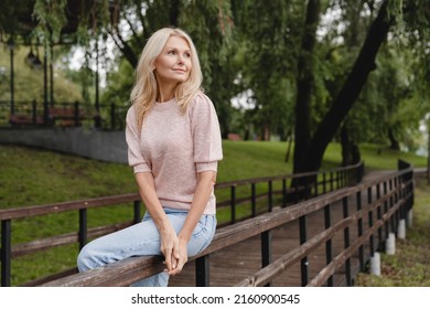 Cropped closeup portrait of a caucasian mature beautiful blonde woman wife walking alone in park forest outdoors spending free time in woods. - Powered by Shutterstock