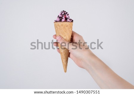 Cropped closeup pov first person you view photo of hand holding yummy with berry taste sugary with raspberry flavor ice cream with cacao drops on top isolated grey background