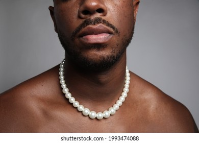 Cropped Close-up Of Shirtless Black Man With Pearl Necklace Over Grey Wall.