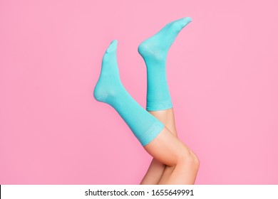 Cropped close-up view of nice vertical feminine legs walking in air wearing blue soft cotton bright cosy socks hosiery isolated over pink pastel color background