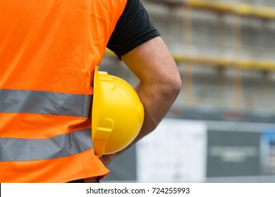 Cropped Construction Worker With Orange Safety Vest Holding A Yellow Helmet