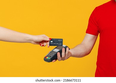Cropped delivery guy employee man wear red T-shirt uniform work as dealer courier hold wireless bank payment terminal customer process acquire credit card payment isolated on plain yellow background