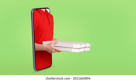 Cropped of delivery man in red workwear holding pizza boxes, standing in huge smartphone over colorful background, panorama with copy space. Food delivery service via modern technology concept