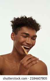 Cropped Of Excited Black Guy Brushing His Teeth With Toothpaste. Young Positive Brunette Curly Man With Naked Torso. Dental Care And Hygiene. Isolated On White Background. Studio Shoot