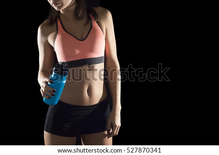 cropped face body detail portrait of young athletic female body of sport woman bottle water posing alone isolated on black background in healthy lifestyle concept